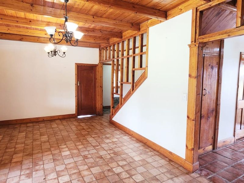 Spacious living area featuring exposed timber beam ceilings, tiled flooring, and traditional timber door frames, offering a rustic and character-filled interior space.
