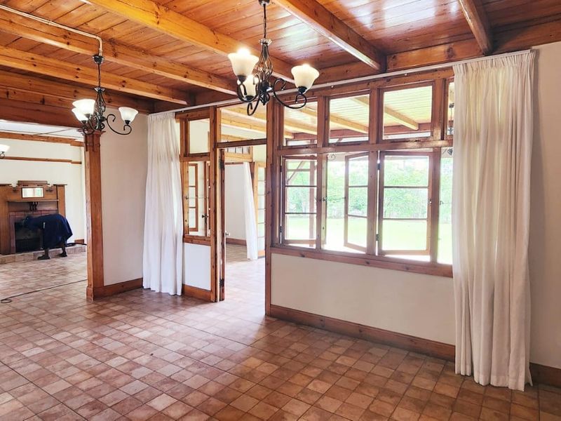 Spacious living area featuring exposed timber ceiling beams, terracotta-style tiled flooring, and a traditional fireplace with a timber mantelpiece.