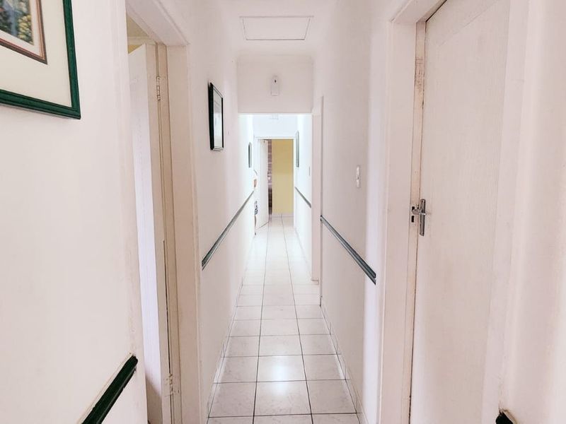 A functional residential hallway featuring tiled flooring and chair rail molding, providing access to multiple rooms within the home.