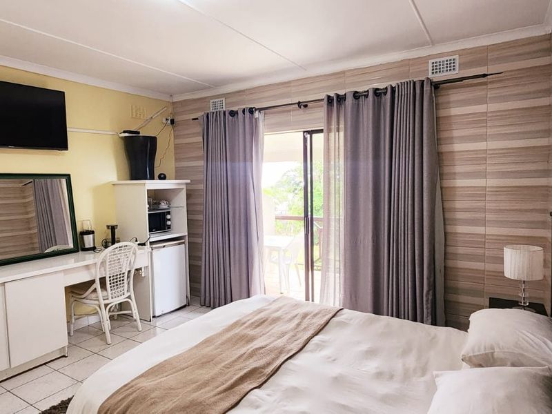 A bedroom featuring tiled flooring, a built-in vanity unit, and a sliding glass door providing access to an outdoor area.