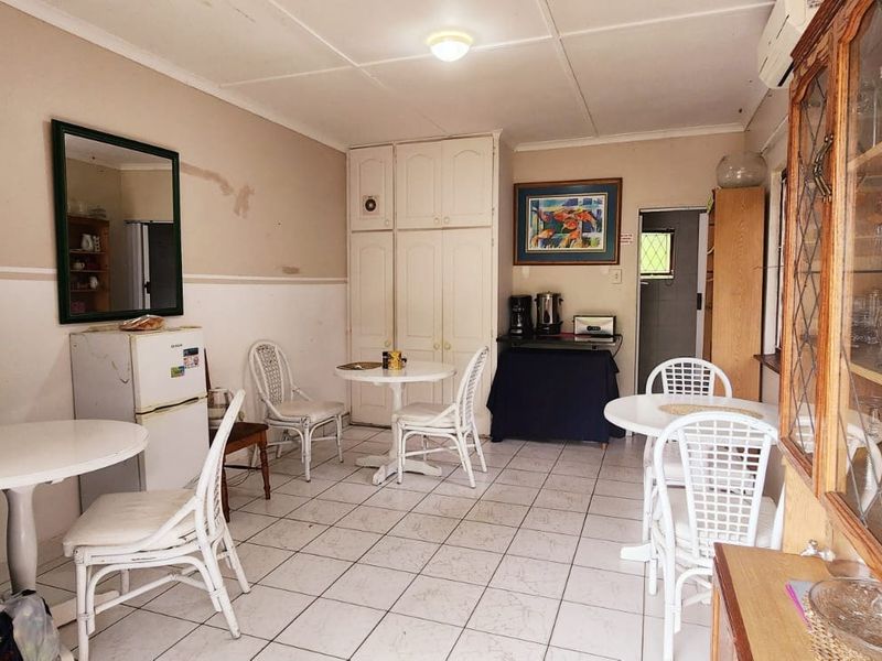 Living area featuring tiled flooring, built-in storage cupboards, and an air conditioning unit, showing signs of wear on the walls.