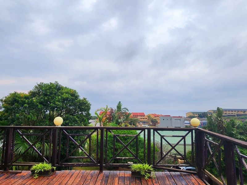 An elevated timber balcony featuring a wooden balustrade and scenic neighbourhood views, providing an open outdoor space for relaxation.