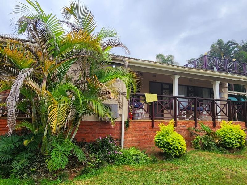 Rear view of the house featuring a covered patio with timber balustrades, brick base, and an external staircase leading to an upper roof terrace.