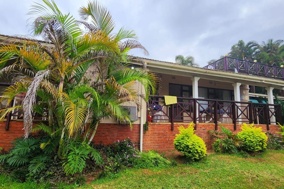 Rear view of the house featuring a covered patio with timber balustrades, brick base, and an external staircase leading to an upper roof terrace.