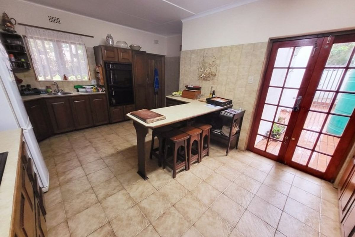 A functional kitchen featuring traditional wooden cabinetry, a built-in double oven, a central island, and direct access to the outdoor area through glass doors.