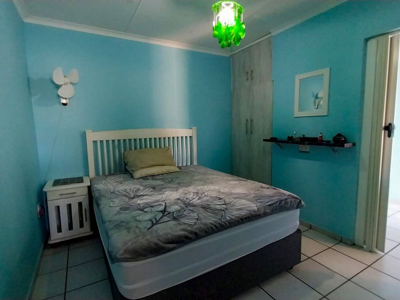 A bedroom featuring tiled flooring, a built-in wardrobe, and a wall-mounted shelf, providing a functional space with potential for modern updates.