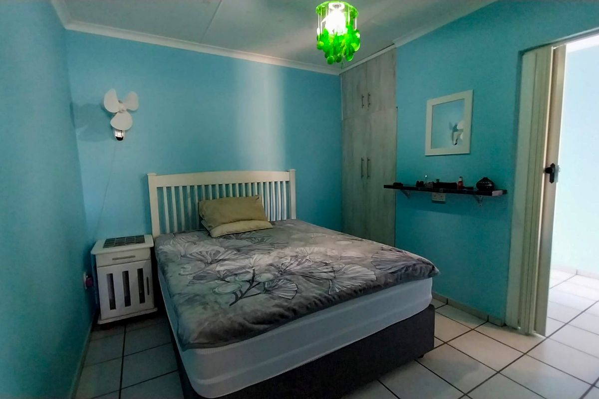A bedroom featuring tiled flooring, a built-in wardrobe, and a wall-mounted shelf, providing a functional space with potential for modern updates.