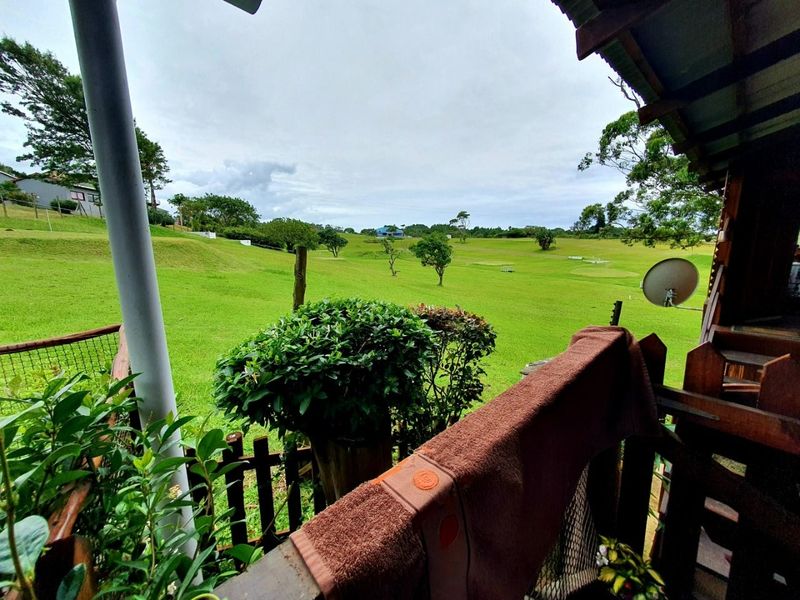 A covered patio area overlooking a large, open green landscape and golf course views.