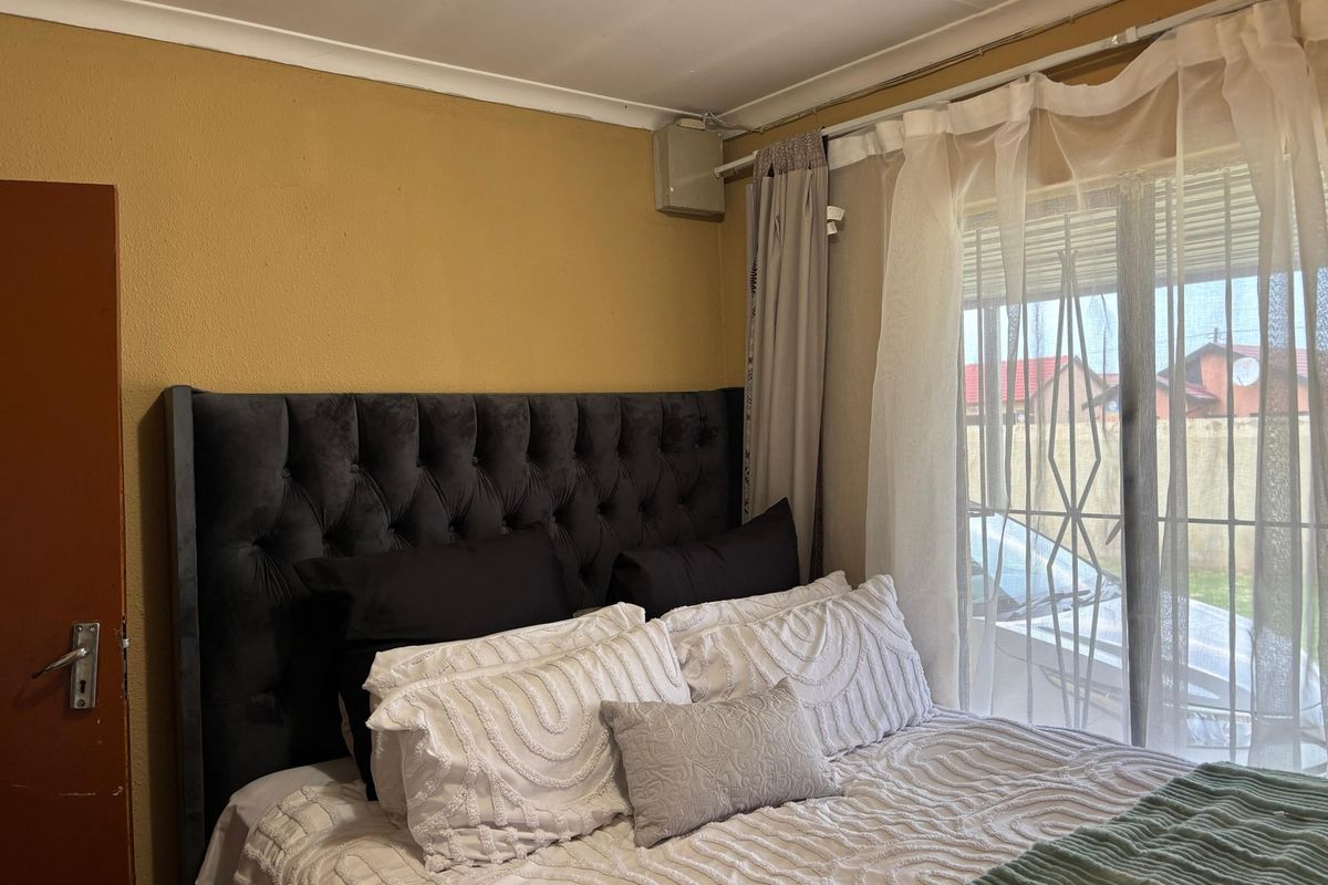 A bedroom featuring a sliding door with an integrated security gate, providing natural light and access to the exterior.