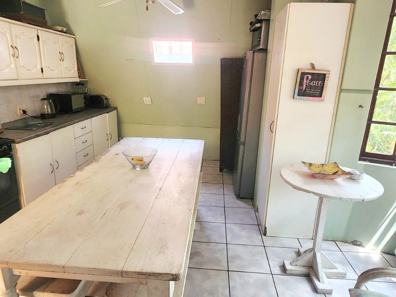 A dated kitchen featuring built-in cabinetry, tiled flooring, and an electric stove, offering potential for modernization and renovation.