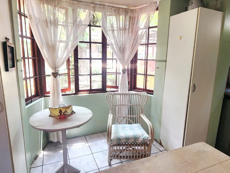 A compact kitchen area featuring a bay window, tiled flooring, and built-in cabinetry, offering potential for a modern update.