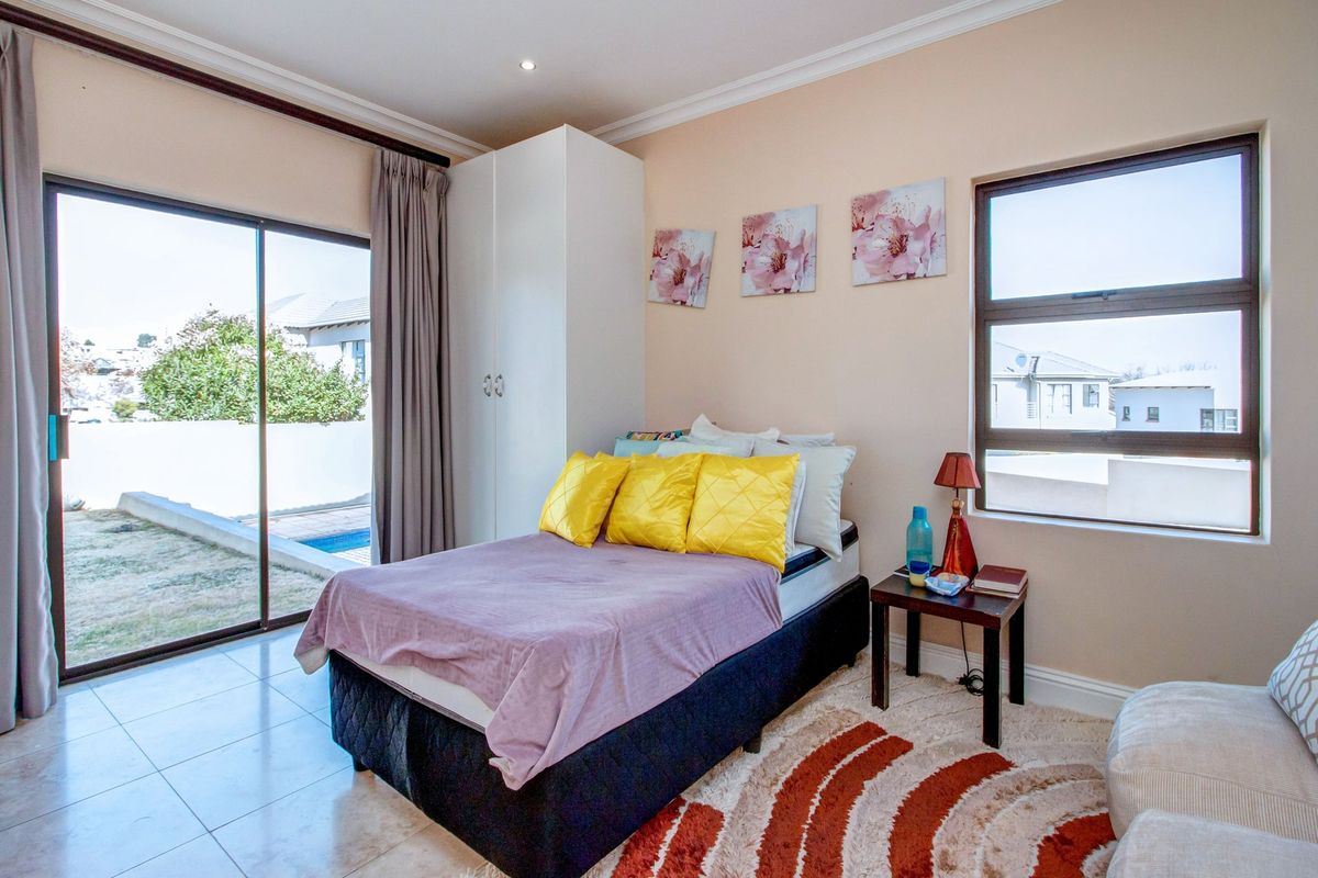 A bright bedroom featuring tiled flooring, a built-in wardrobe, and a sliding glass door providing direct access to the outdoor pool area.
