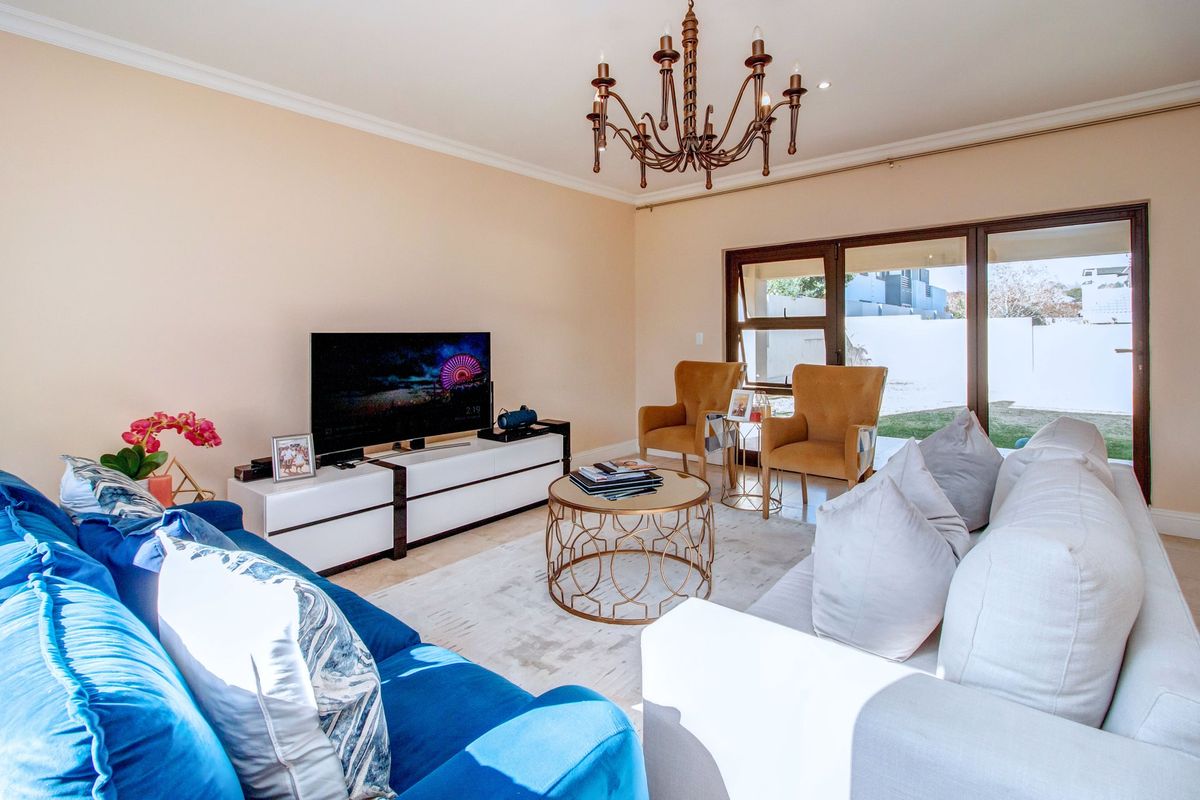 A bright and well-maintained living room featuring a decorative chandelier, recessed lighting, and large sliding glass doors providing access to the outdoor area.