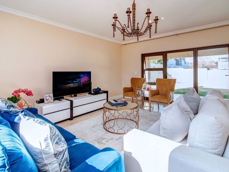 A bright and well-maintained living room featuring a decorative chandelier, recessed lighting, and large sliding glass doors providing access to the outdoor area.