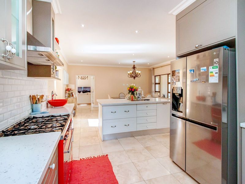 Spacious open-plan kitchen featuring a central island, stone countertops, subway tile backsplash, and modern cabinetry, flowing seamlessly into the adjacent dining and living areas.
