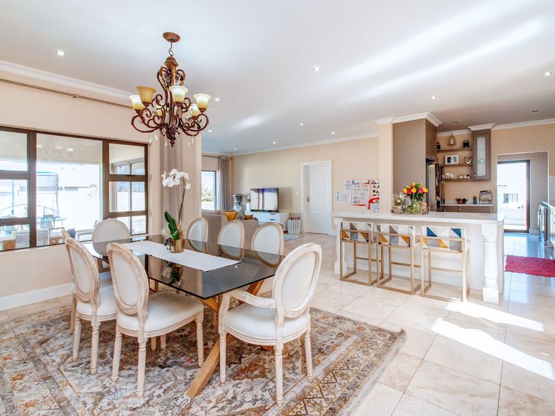 Spacious open-plan living and dining area featuring a modern kitchen with a central island, tiled floors, and abundant natural light through large sliding doors.