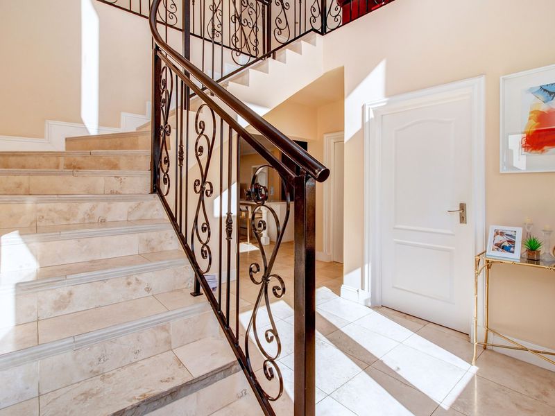 A bright and welcoming entrance hall featuring a tiled staircase with an elegant wrought iron balustrade and neutral wall finishes.