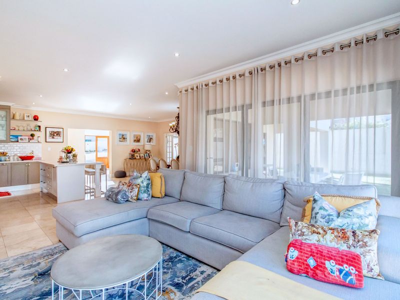 Spacious open-plan living area featuring tiled floors, recessed lighting, and a modern kitchen with a central island, seamlessly connecting to the outdoor patio.