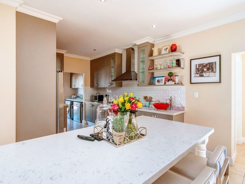 Modern kitchen featuring a stone-topped island, subway tile backsplash, and integrated cabinetry, with an adjacent scullery area for additional utility.
