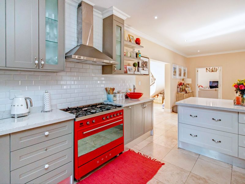 Modern kitchen featuring grey shaker-style cabinetry, subway tile backsplash, stone countertops, a central island, and a distinctive red Smeg gas range.
