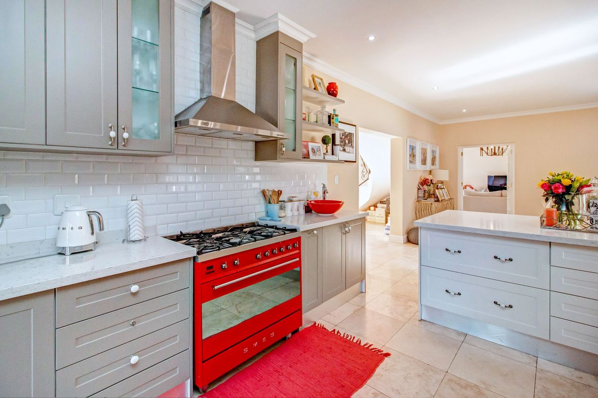 Modern kitchen featuring grey shaker-style cabinetry, subway tile backsplash, stone countertops, a central island, and a distinctive red Smeg gas range.