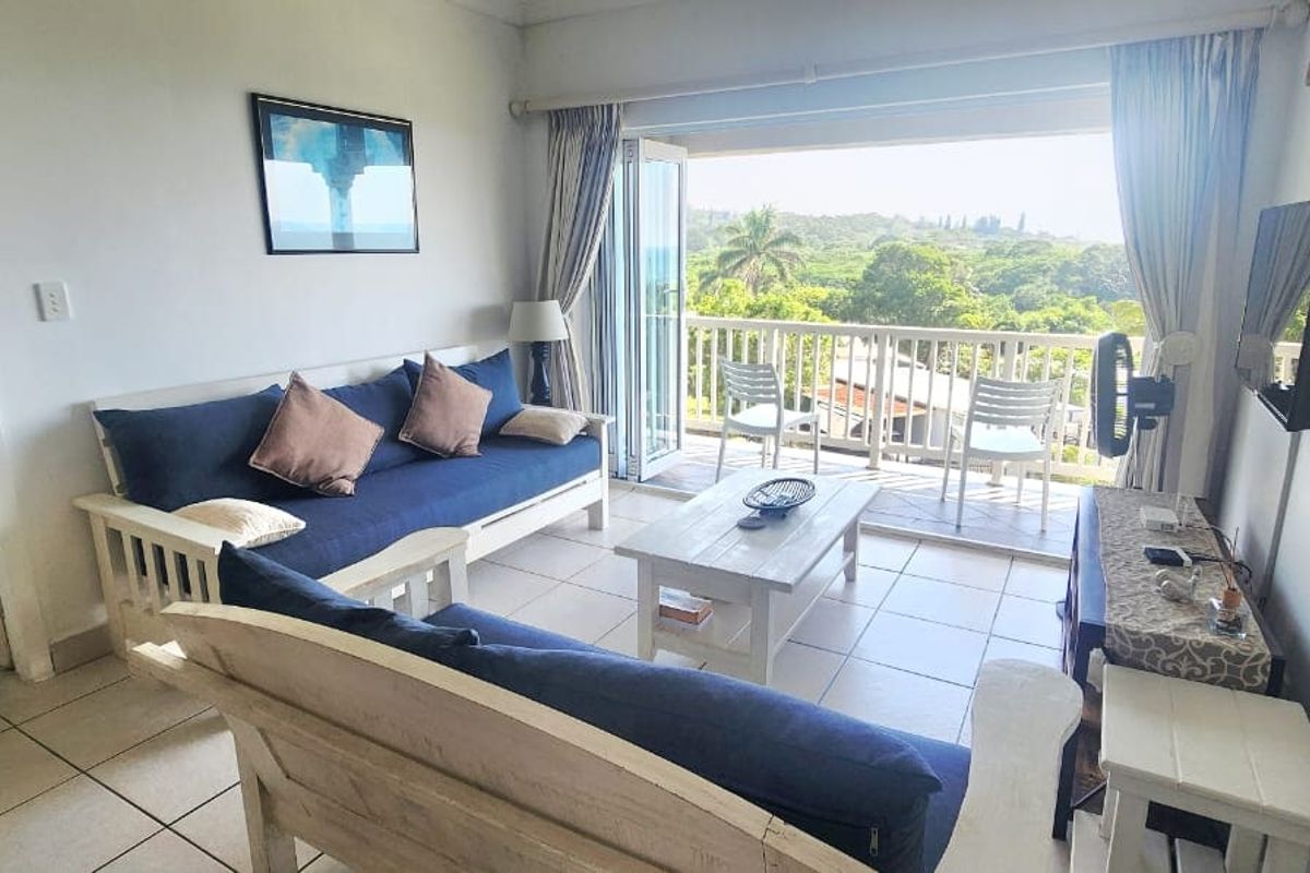 A bright living room featuring tiled flooring and bi-fold doors opening onto a balcony with scenic views.