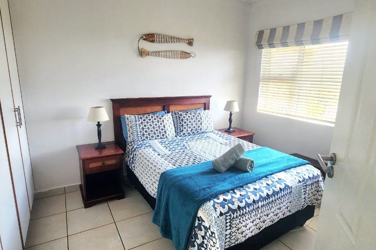 A functional bedroom featuring built-in cupboards, tiled flooring, and a window with venetian blinds, providing a clean and practical living space.