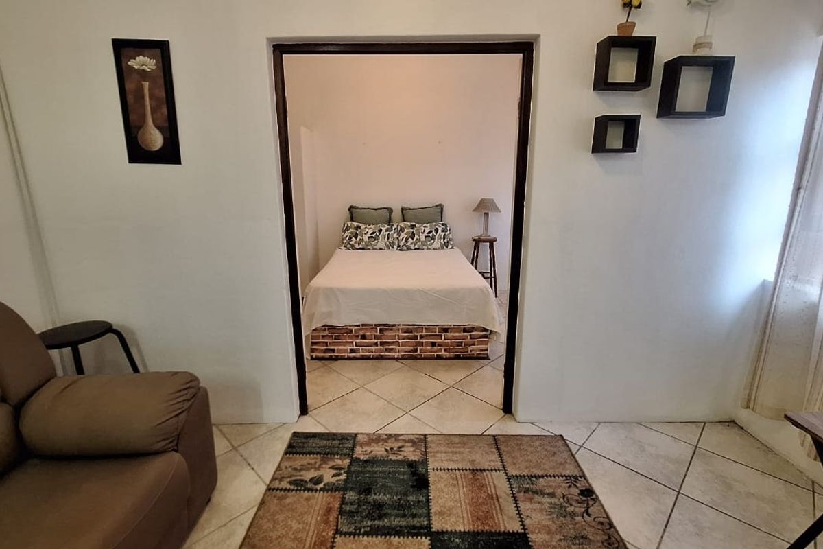 A view from the living area into the adjacent bedroom, featuring tiled flooring and a clear transition between the two living spaces.