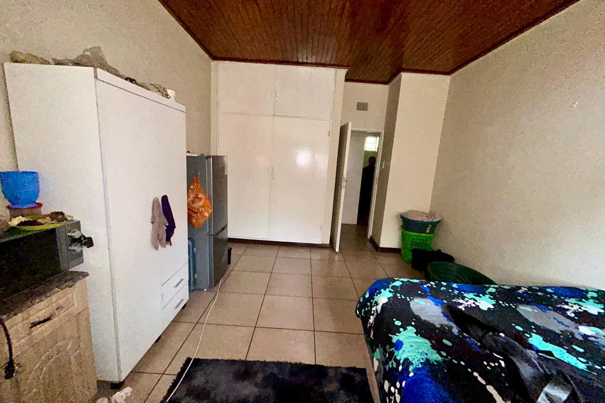 A bedroom featuring tiled flooring, built-in cupboards, and a timber-paneled ceiling, requiring cosmetic updates to improve its overall condition and appeal.