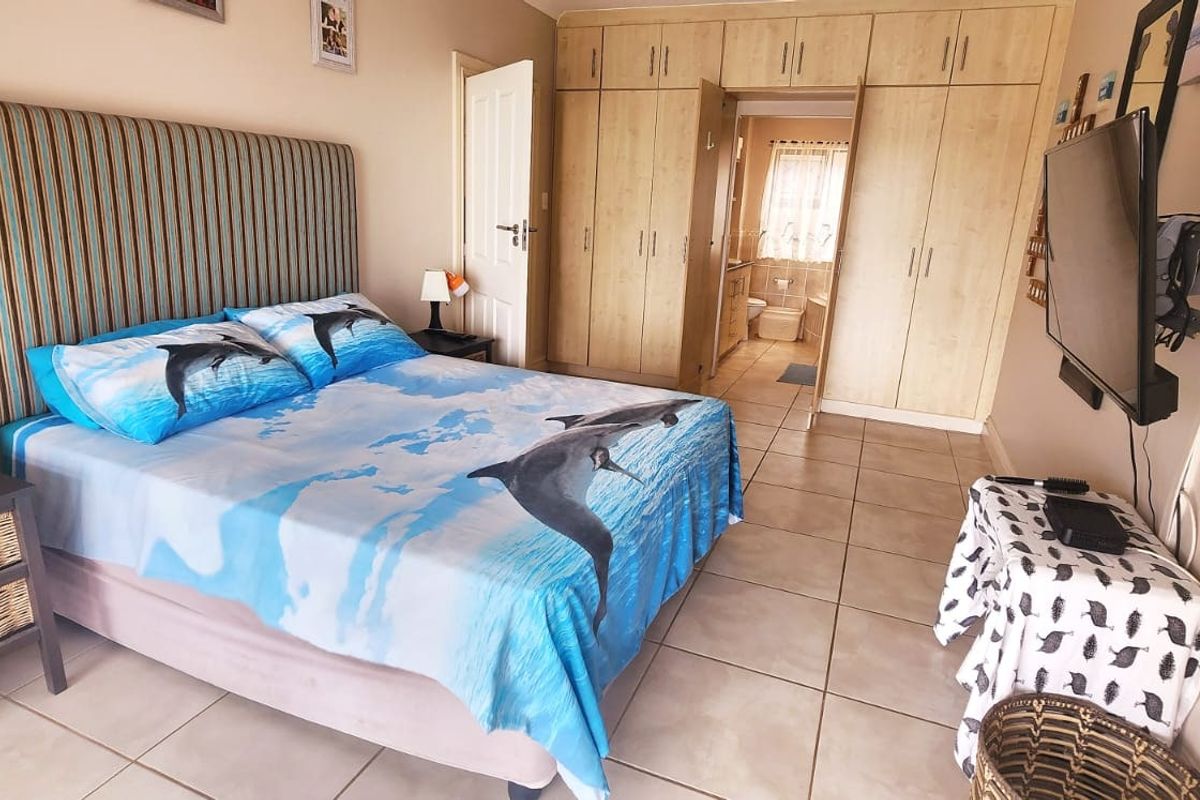A bedroom featuring built-in cupboards, tiled flooring, and direct access to an en-suite bathroom.