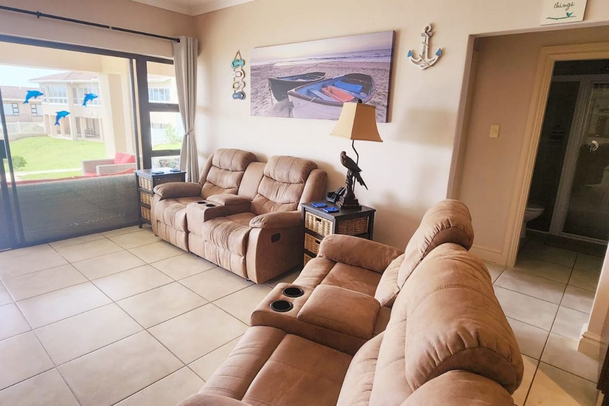 A living room featuring tiled flooring and a large sliding glass door providing access to an outdoor patio area.