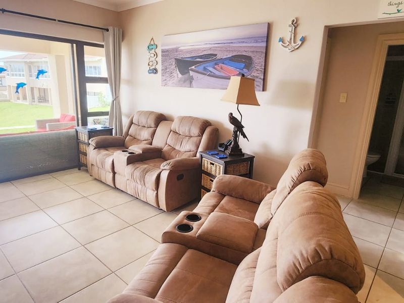 A living room featuring tiled flooring and a large sliding glass door providing access to an outdoor patio area.