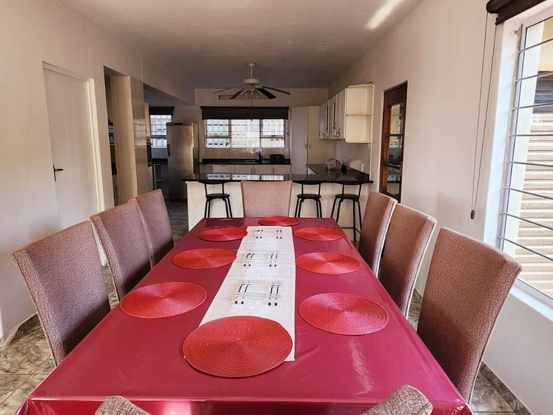 Open plan dining and kitchen area featuring tiled flooring, a central kitchen island, and neutral wall finishes.