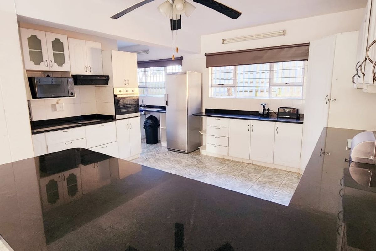 Functional kitchen featuring dark granite countertops, white cabinetry, built-in oven, and tiled flooring, offering a clean and practical workspace.