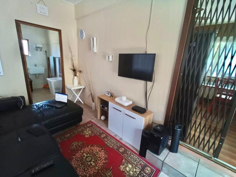 A living room area featuring tiled flooring and a security gate leading to an adjacent space.