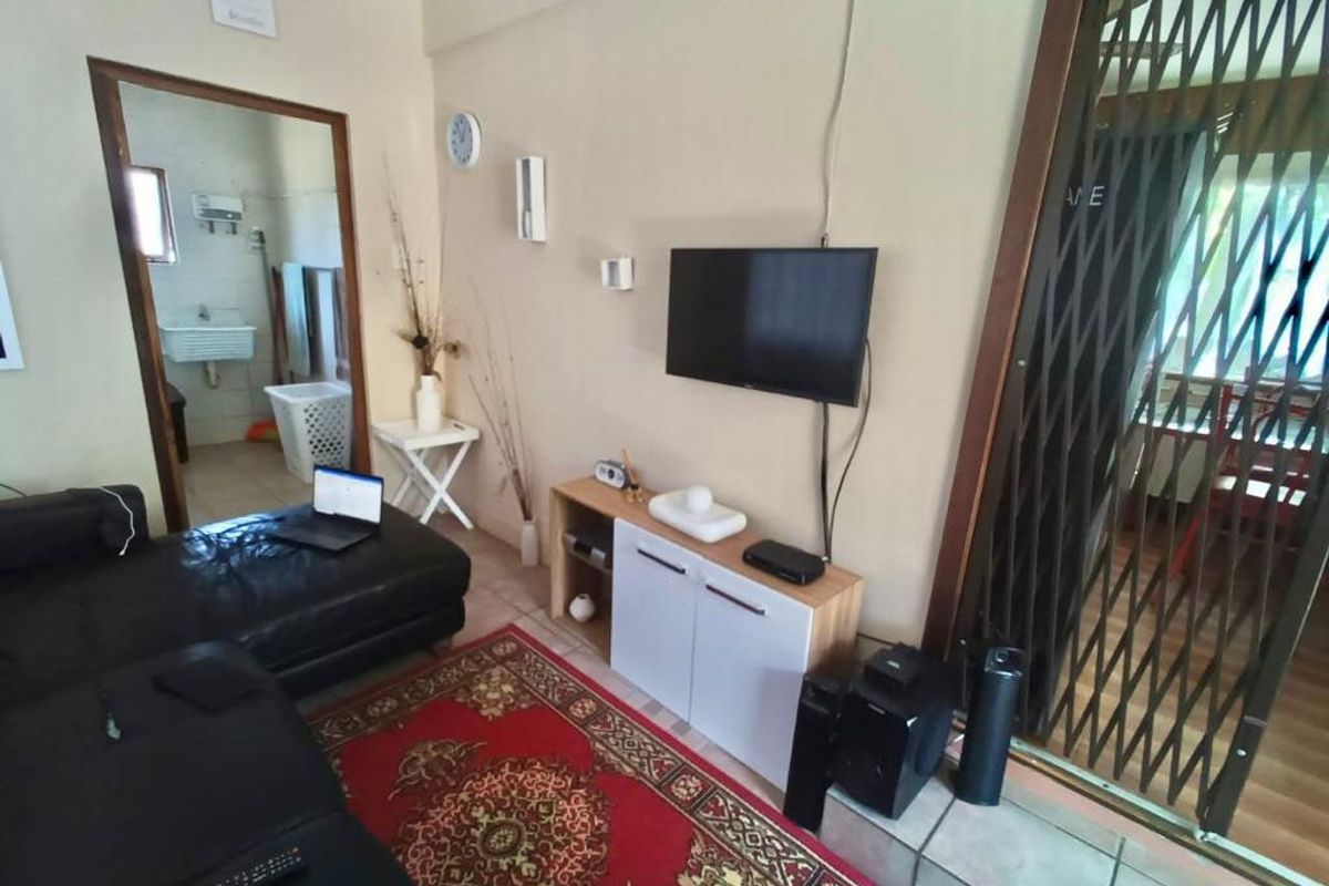 A living room area featuring tiled flooring and a security gate leading to an adjacent space.