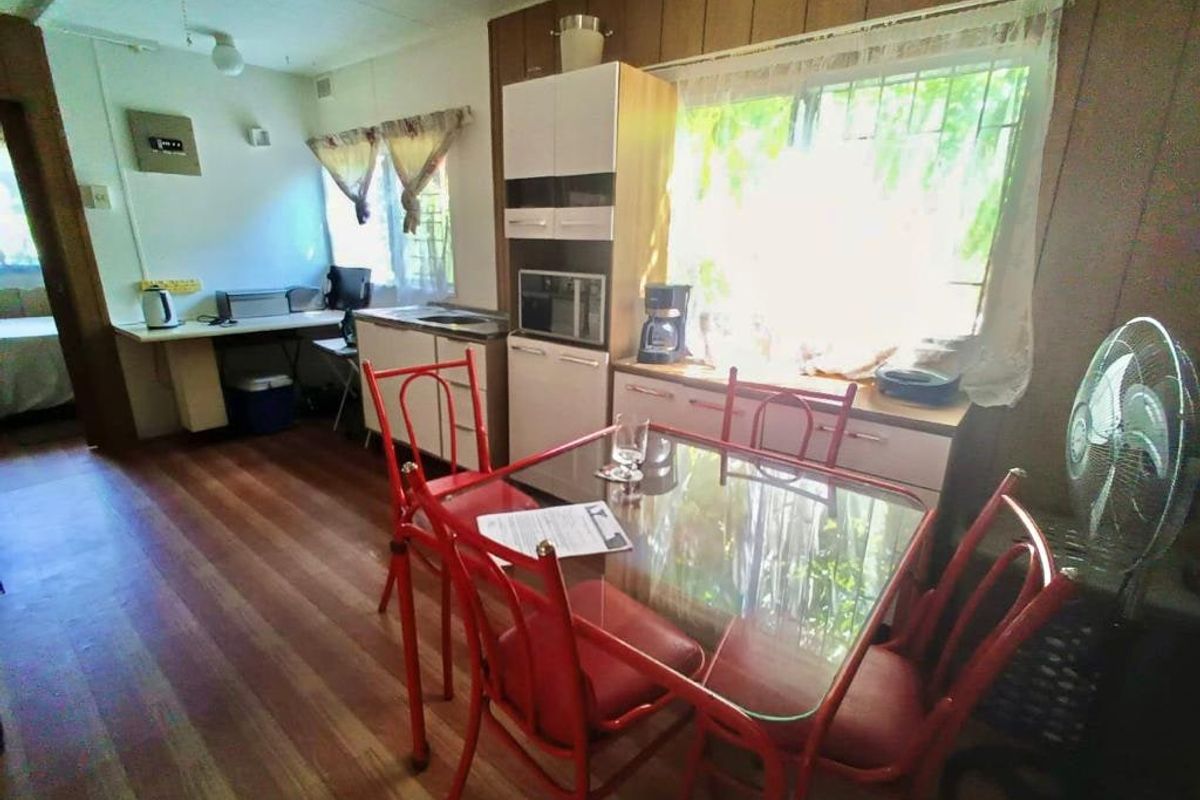 A dated kitchen area featuring built-in cabinetry, laminate countertops, and timber flooring, offering potential for a modern renovation.
