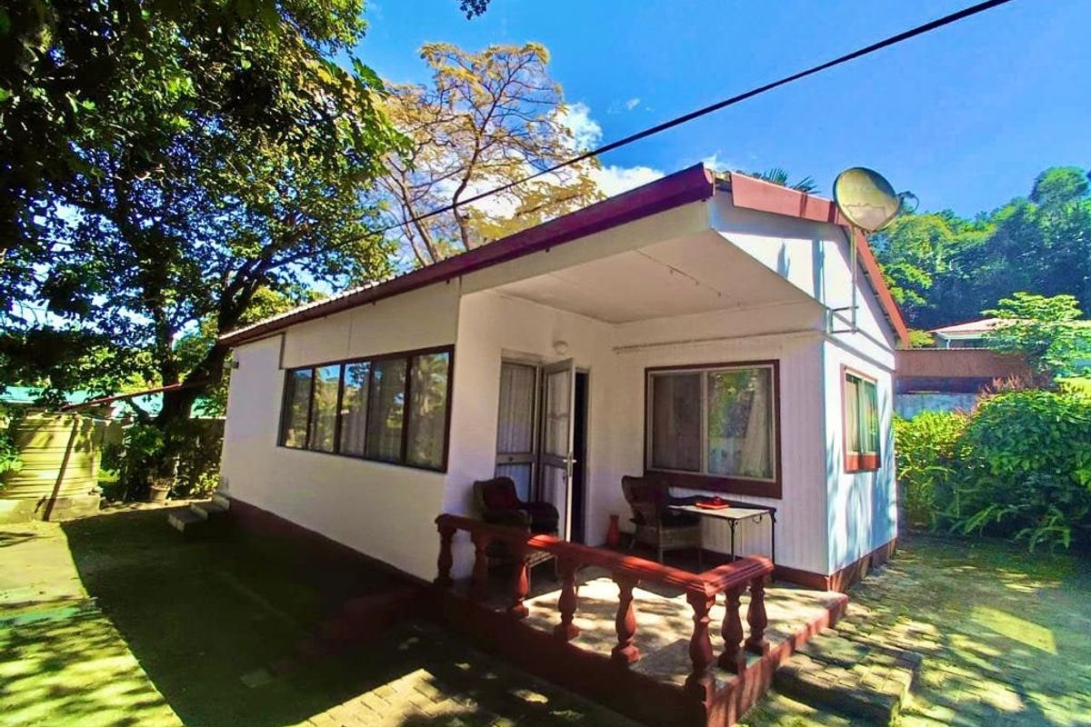 Rear view of the townhouse featuring a covered patio with a concrete balustrade and paved outdoor area.