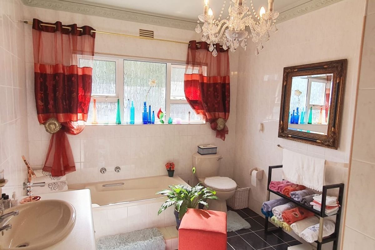 A traditional bathroom featuring a built-in bathtub, pedestal basin, toilet, and decorative crown molding, finished with wall-to-wall tiling.