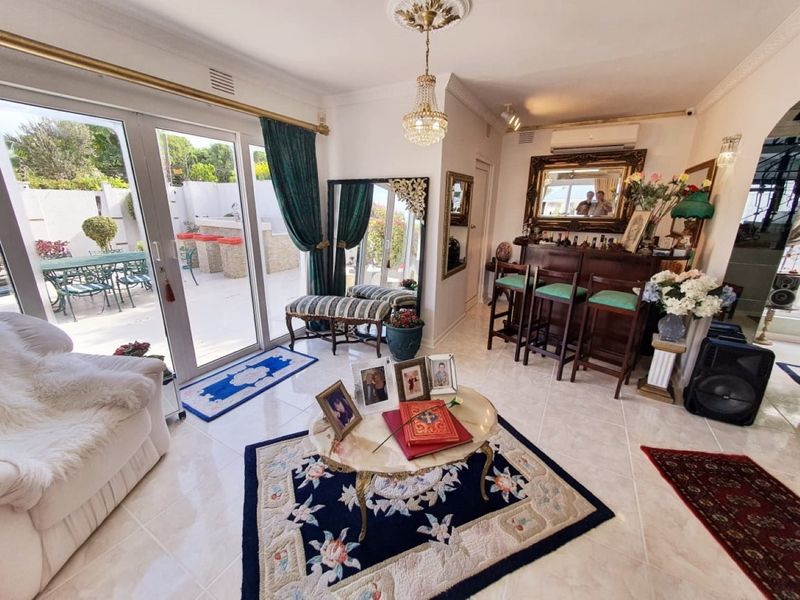 A bright living area featuring large sliding glass doors that open onto a patio, tiled flooring, and a built-in bar area.