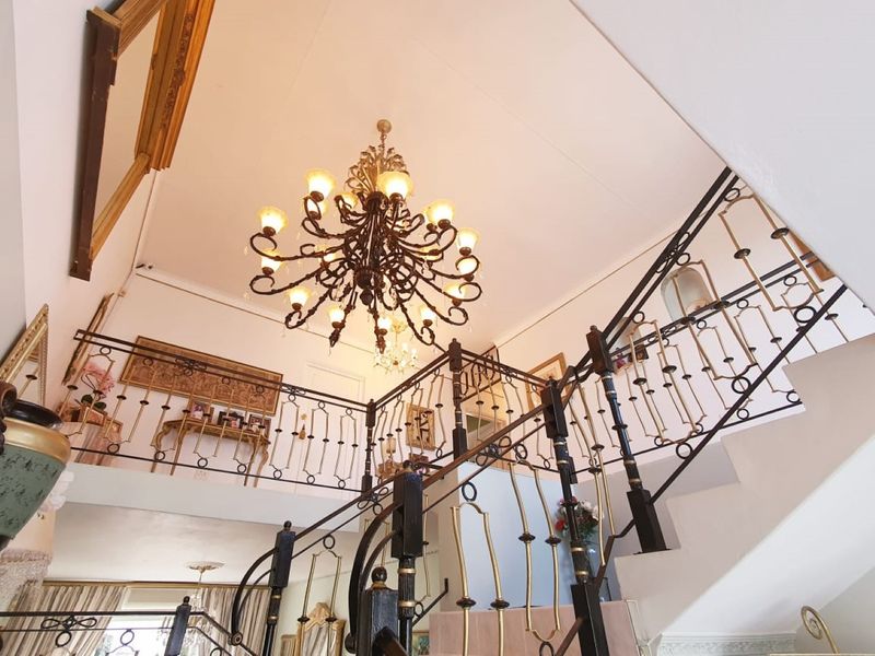 Grand entrance hall featuring a decorative wrought iron staircase railing and an ornate multi-tiered chandelier.