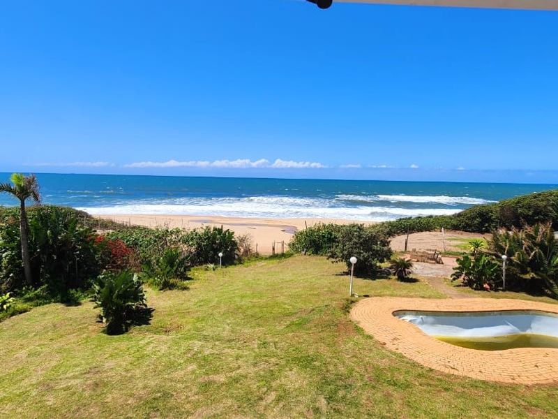 Elevated view of the backyard featuring a swimming pool, landscaped garden, and direct access to the beach and ocean.