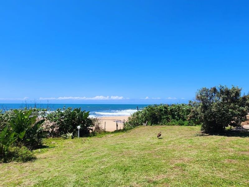 A scenic outdoor garden area featuring expansive ocean views, well-maintained lawn, and established coastal vegetation.