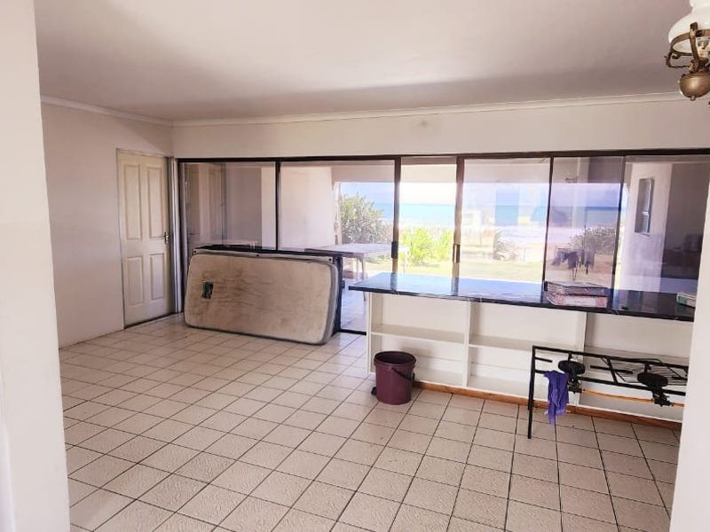 An open-plan living area featuring tiled flooring, built-in counter space, and large sliding glass doors providing access to the outdoor area.