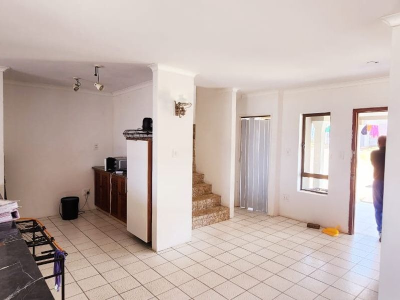 Open plan living area featuring tiled flooring, a breakfast counter, and direct access to the exterior.
