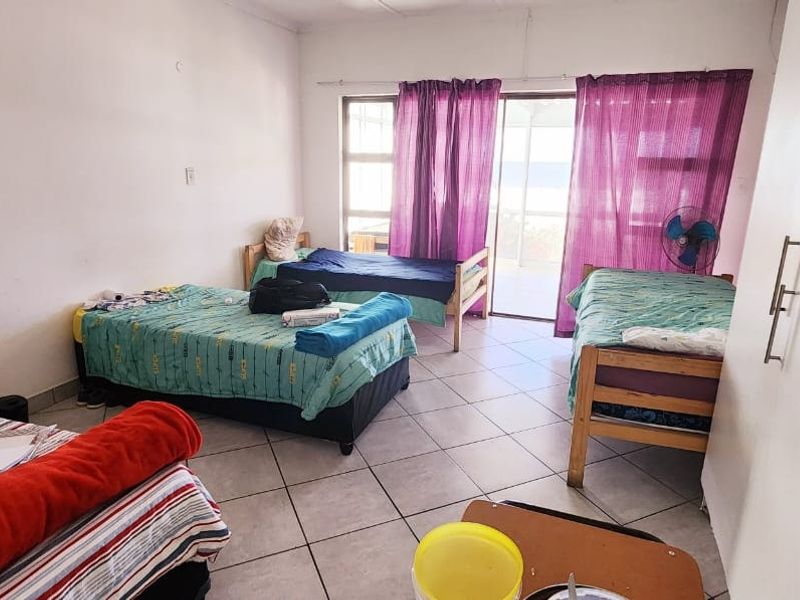 A spacious bedroom featuring tiled flooring, built-in cupboards, and large sliding glass doors providing access to an outdoor area.