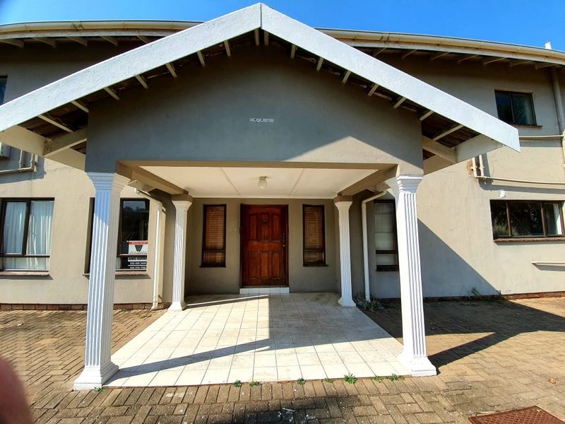 Front entrance of the house featuring a covered porch with decorative columns, tiled flooring, and a solid timber front door.