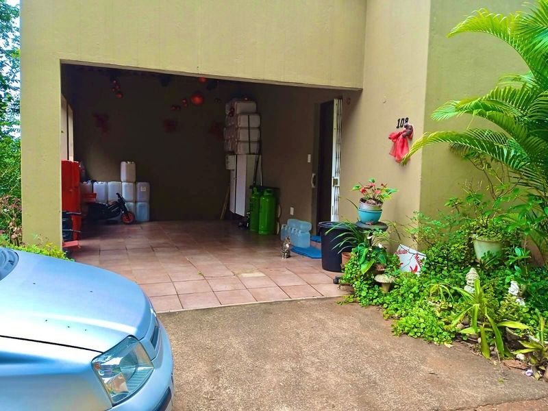 A covered garage area with tiled flooring, providing sheltered parking space for the townhouse.