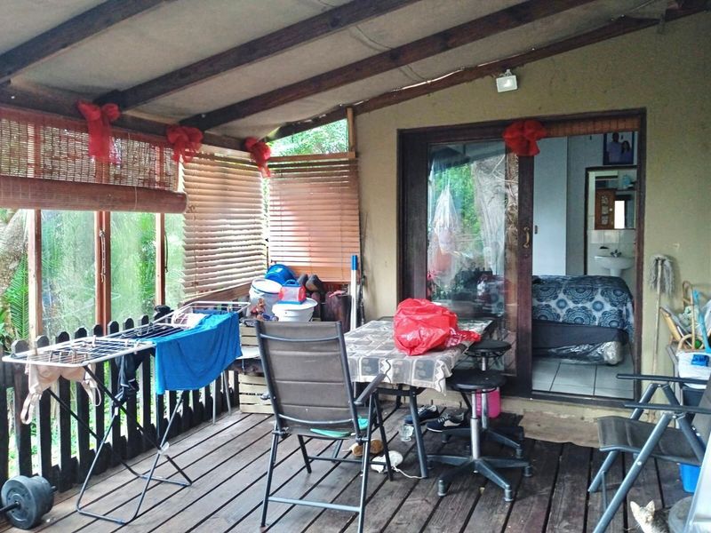 A covered outdoor patio featuring timber decking and a timber roof structure, providing direct access to the interior living space through sliding glass doors.