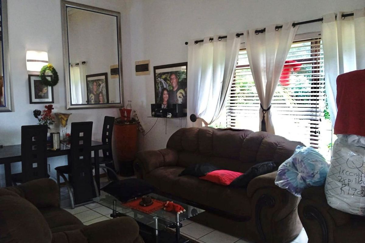 A living room area featuring tiled flooring and window treatments, providing a functional space for relaxation and dining.